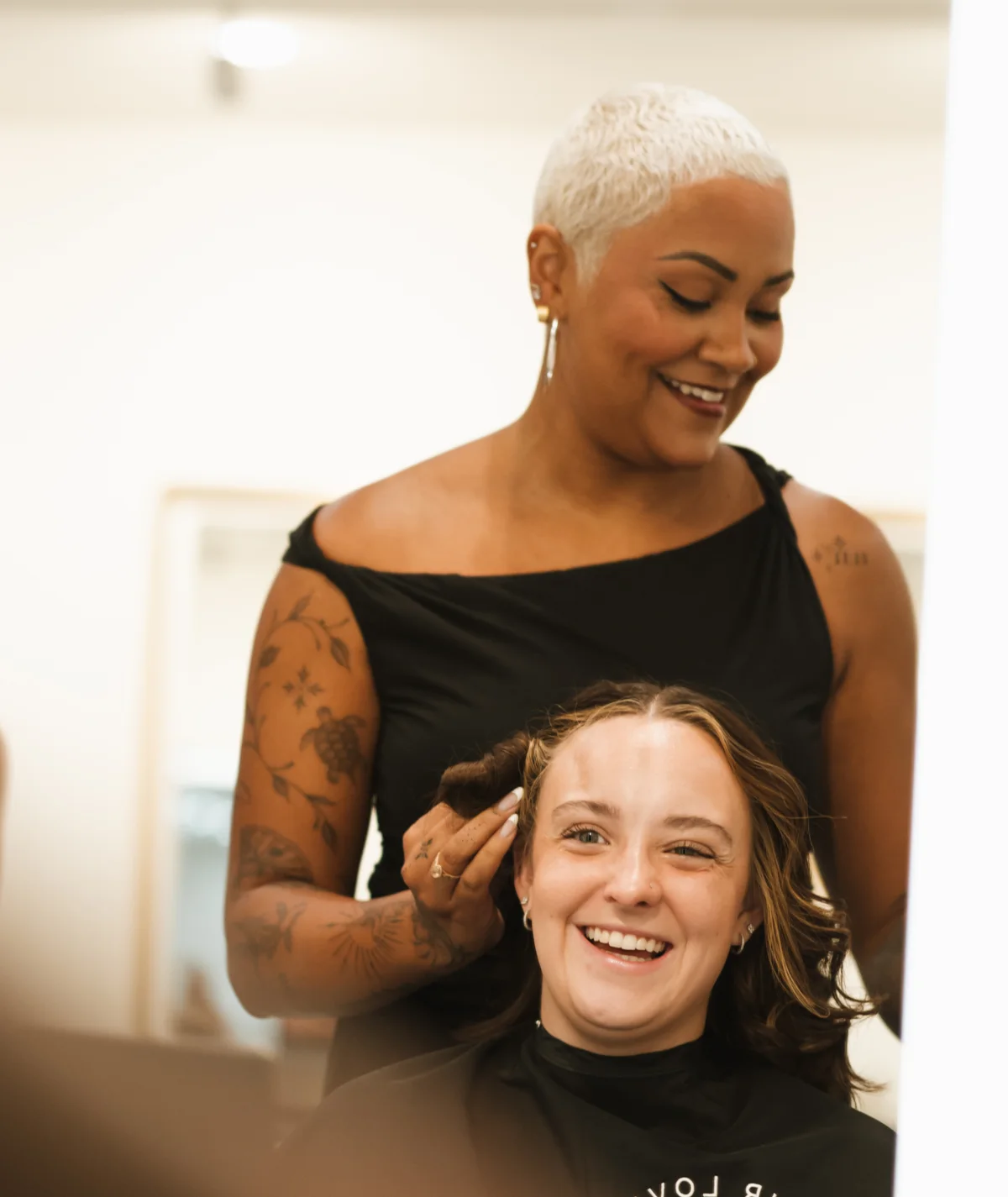 A stylist working with a smiling client in a salon suite
